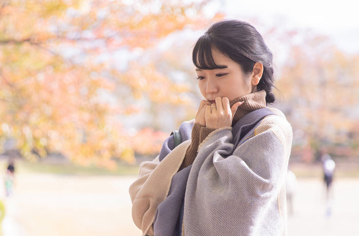 寒さに身をすくめる女性―寒い季節に気をつけたい歯の食いしばりと対策